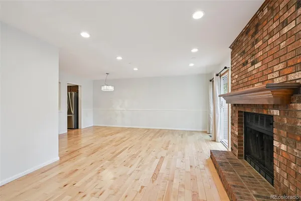 a view of an empty room with wooden floor fireplace and a window
