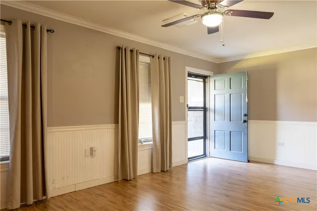 a view of an empty room with wooden floor and a window