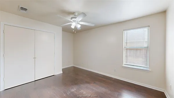 a view of an empty room with a window and wooden floor