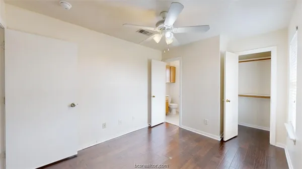 an empty room with wooden floor closet and fan