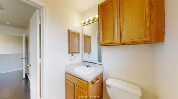 a bathroom with a toilet sink vanity and mirror
