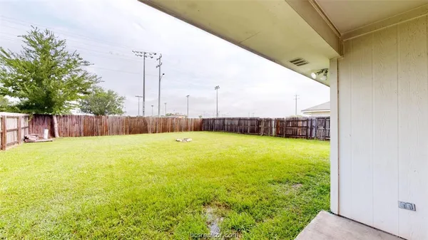 a view of a swimming pool with a yard and a large tree