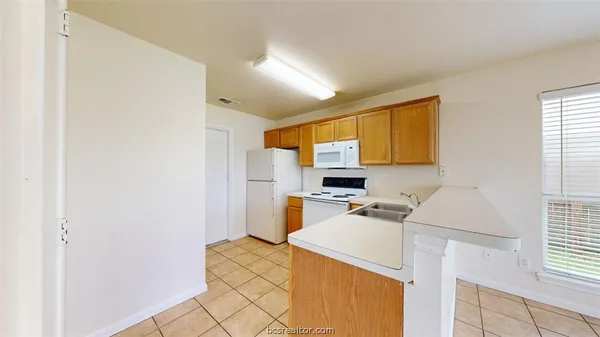 a kitchen with a refrigerator a stove a sink dishwasher and wooden cabinets