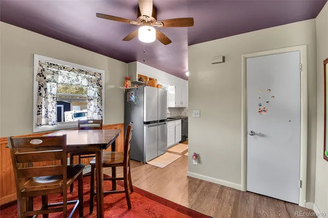 a dining room with stainless steel appliances kitchen island granite countertop a table chairs and a refrigerator