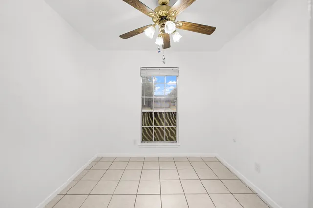 a view of an empty room and chandelier fan