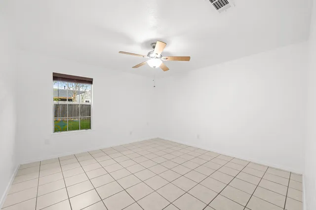 an empty room with windows and ceiling fan