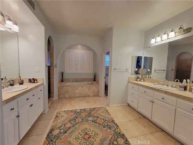 a bathroom with a double vanity sink mirror and bathtub