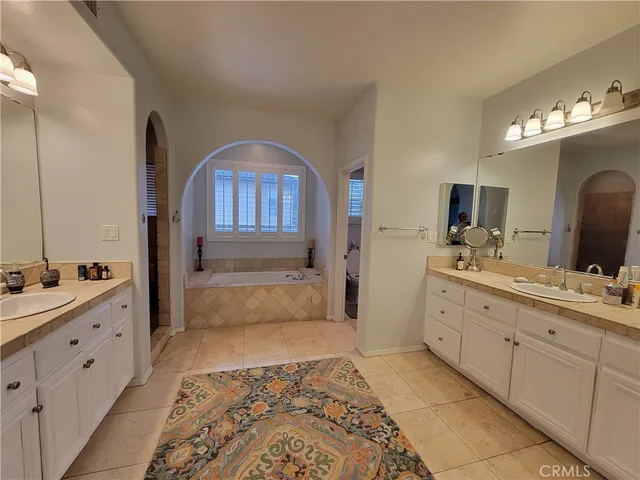 a bathroom with a double vanity sink mirror and bathtub