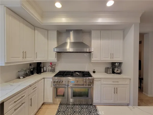 a kitchen with stainless steel appliances granite countertop a sink dishwasher and white cabinets with wooden floor