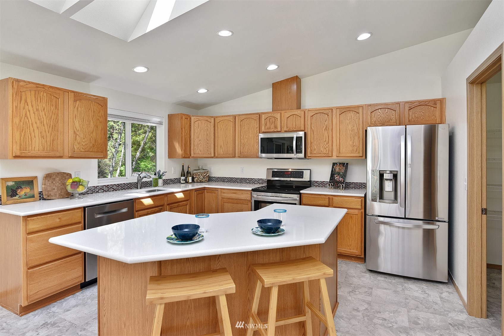 8963 Miller Road Northeast Bainbridge Island, WA 98110 - Photo 14 of 35 a kitchen with stainless steel appliances a stove a sink a refrigerator and cabinets