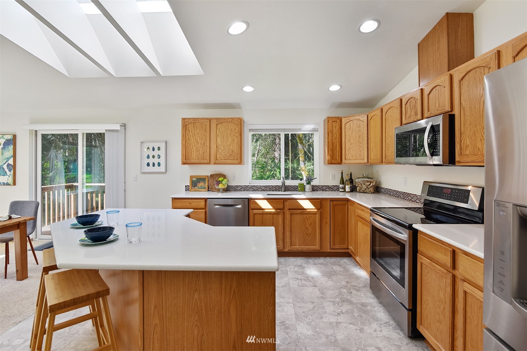 8963 Miller Road Northeast Bainbridge Island, WA 98110 - Photo 15 of 35 a kitchen with stainless steel appliances granite countertop a sink a stove top oven a counter space and cabinets