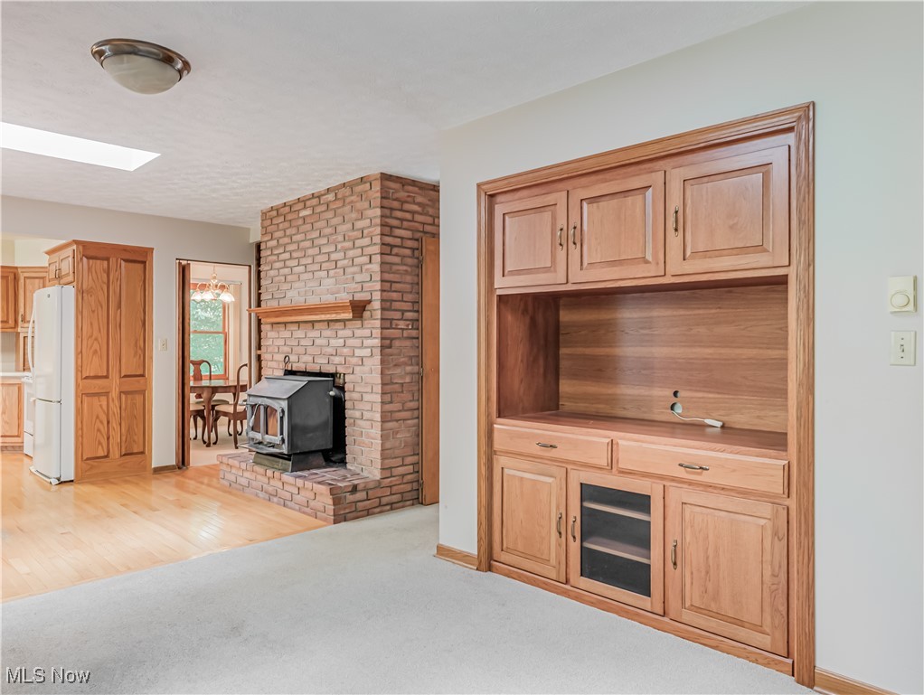 3087 Baughman Road Clinton, OH 44216 - Photo 11 of 24 Unfurnished living room featuring a wood stove, a notable chandelier, and light hardwood / wood-style flooring