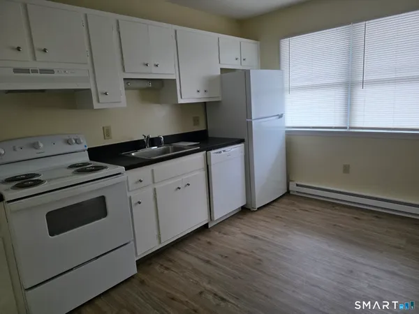 a kitchen with granite countertop white cabinets and white appliances