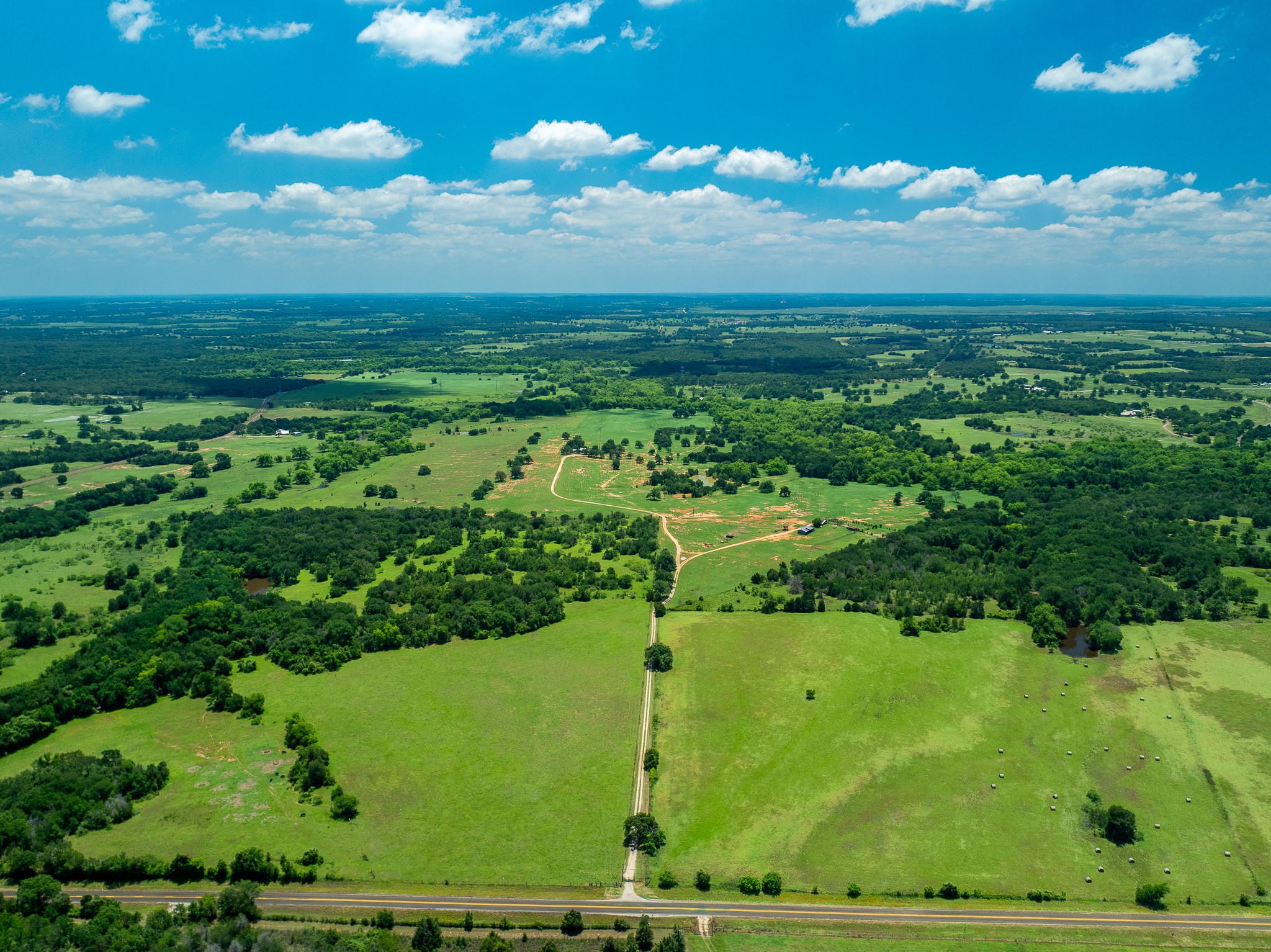 Vast green pastures and wooded expanses define this peaceful rural landscape.