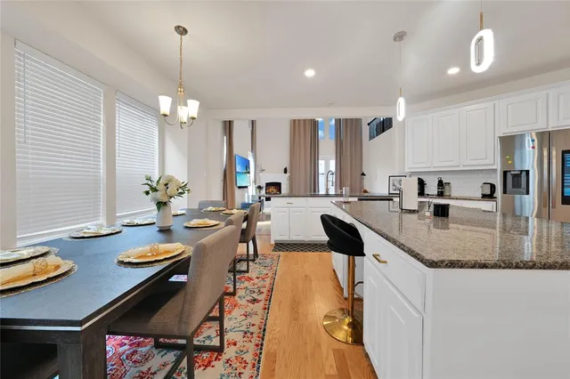 a kitchen with stainless steel appliances granite countertop a sink a stove a refrigerator and island with wooden floor