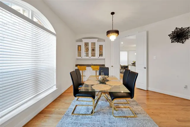 a dining room with wooden floor a chandelier a wooden table and chairs