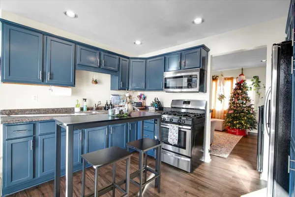 a kitchen with granite countertop a stove top oven microwave and refrigerator