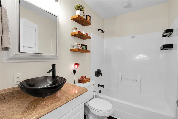 a bathroom with a granite countertop sink a toilet and a mirror