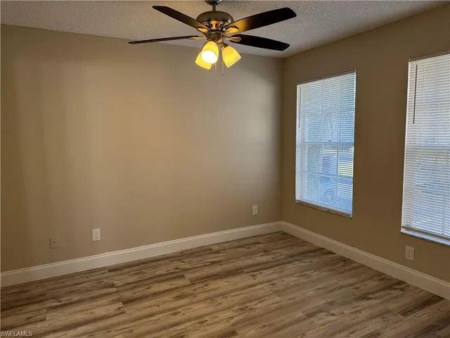 a view of an empty room with window and wooden floor