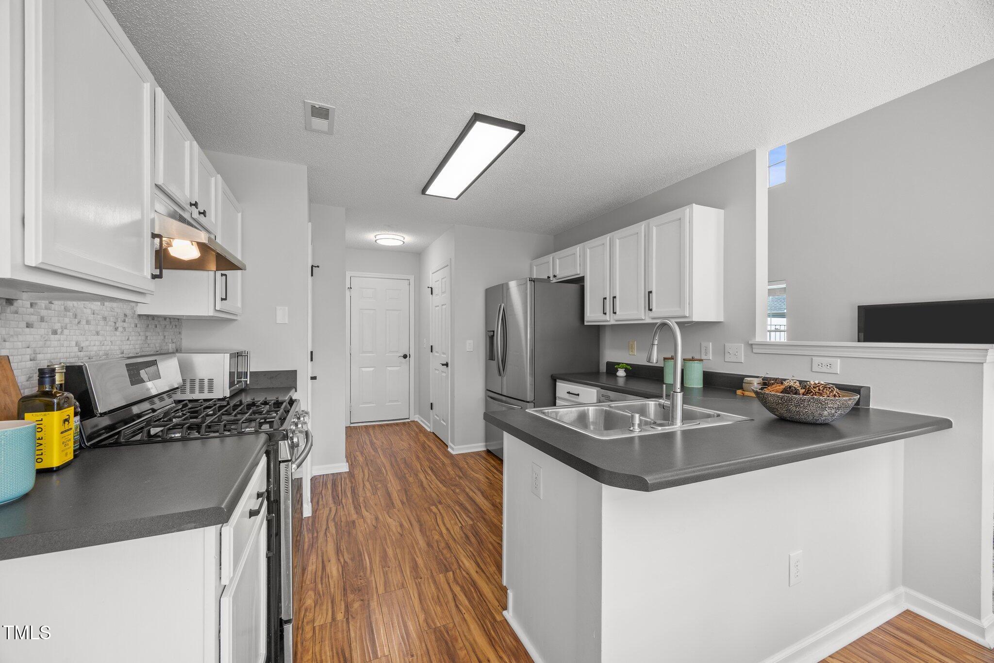 5300 Roan Mountain Place Raleigh, NC 27613 - Photo 10 of 27 a kitchen with stainless steel appliances granite countertop a sink stove refrigerator and cabinets