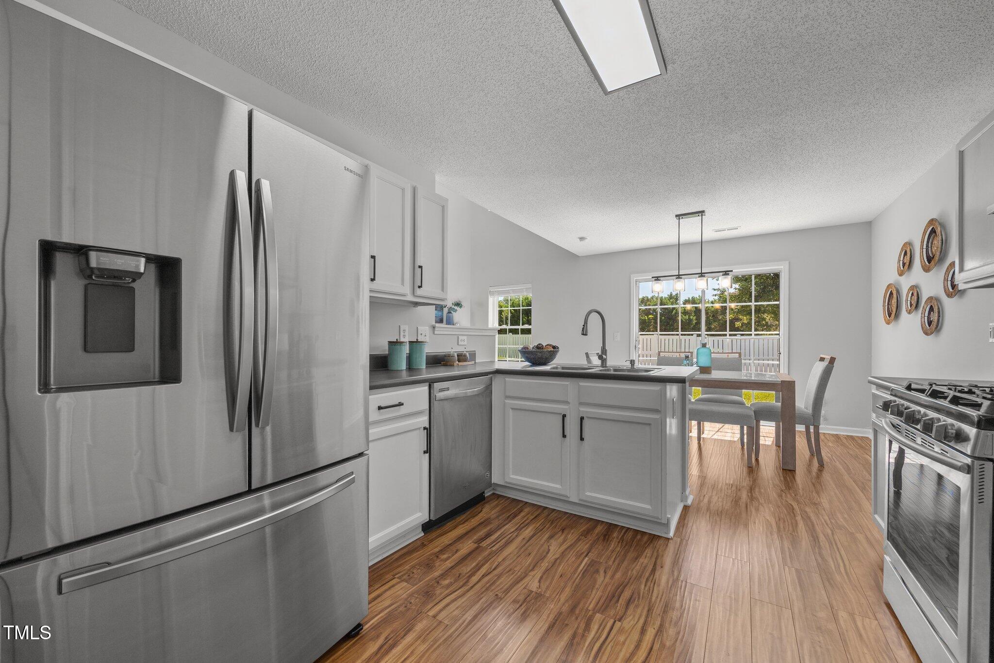 5300 Roan Mountain Place Raleigh, NC 27613 - Photo 11 of 27 a kitchen with white cabinets and stainless steel appliances