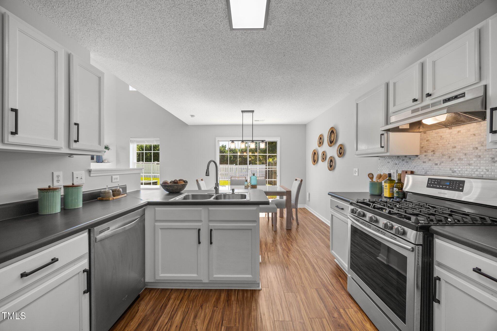 5300 Roan Mountain Place Raleigh, NC 27613 - Photo 12 of 27 a kitchen with granite countertop a sink a counter space appliances and cabinets