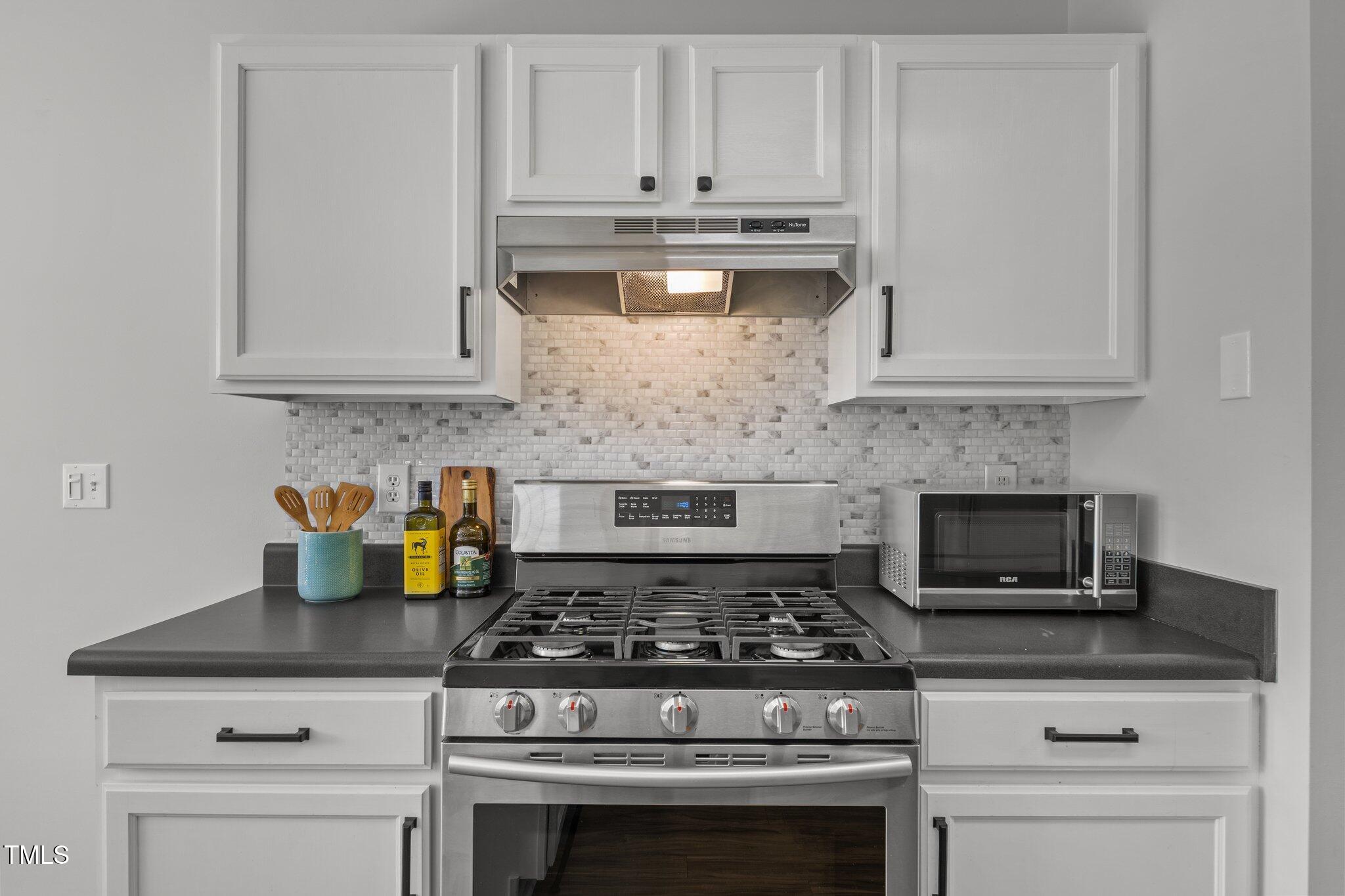 5300 Roan Mountain Place Raleigh, NC 27613 - Photo 13 of 27 a kitchen with white cabinets and appliances