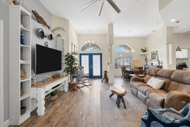 a kitchen with stainless steel appliances kitchen island granite countertop a refrigerator a stove a dining table and chairs with wooden floor