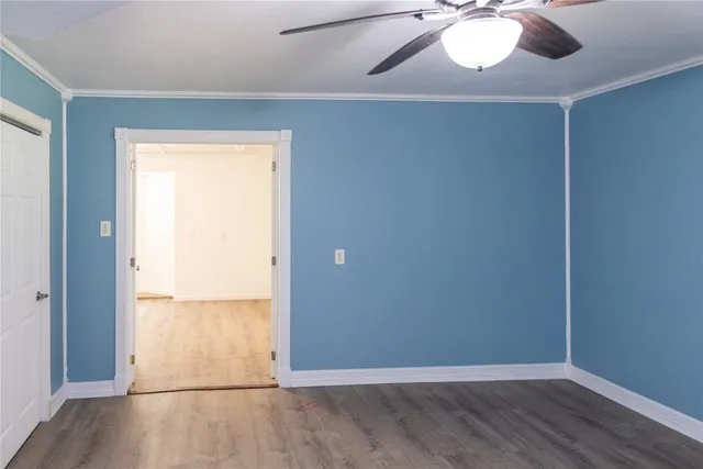 an empty room with wooden floor fan and windows