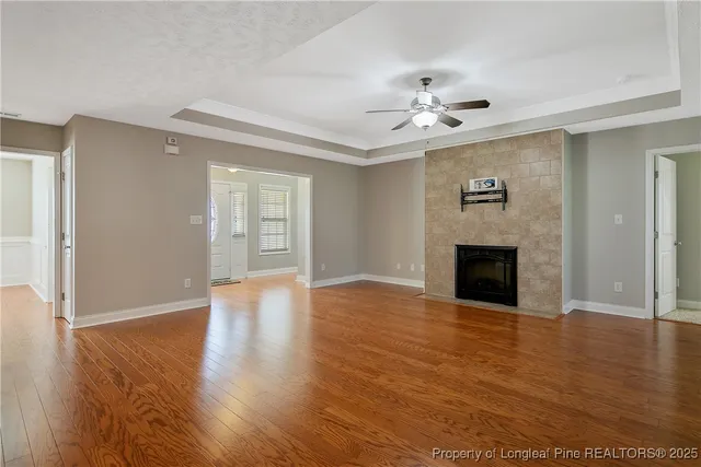 a view of an empty room with wooden floor and a fireplace