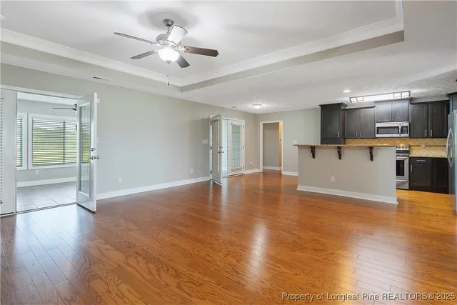 a view of an empty room with kitchen and a window