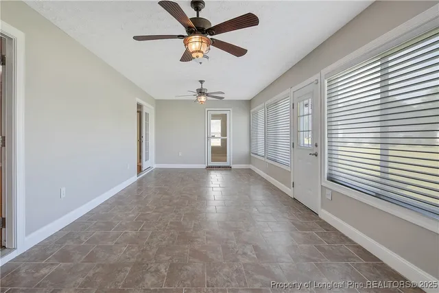an empty room with windows and ceiling fan