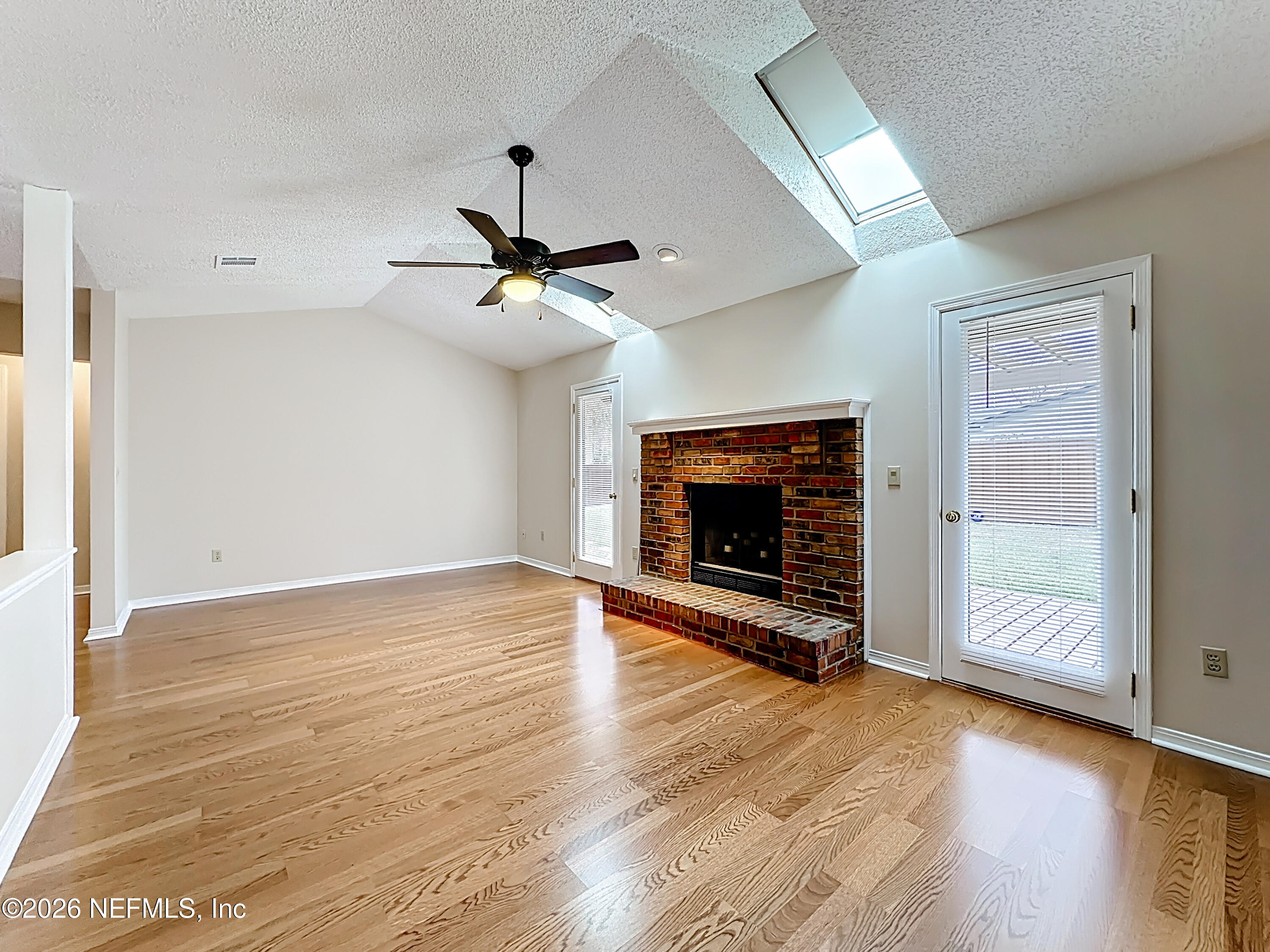 10298 Lone Star Road Jacksonville, FL 32225 - Photo 7 of 42 an empty room with wooden floor fireplace and windows