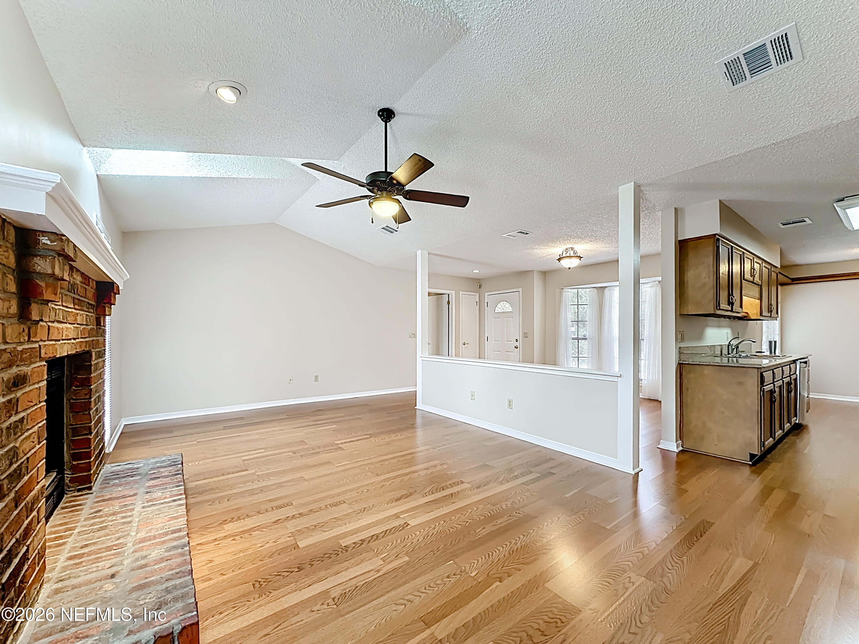 10298 Lone Star Road Jacksonville, FL 32225 - Photo 10 of 42 a view of an empty room and kitchen with wooden floor and a ceiling fan