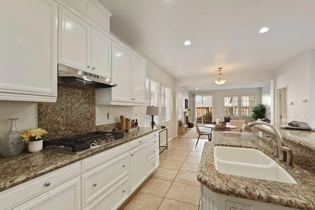 a large kitchen with granite countertop a sink white cabinets and a granite counter tops