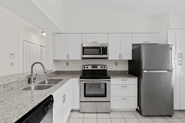 a kitchen with granite countertop a refrigerator stove and sink