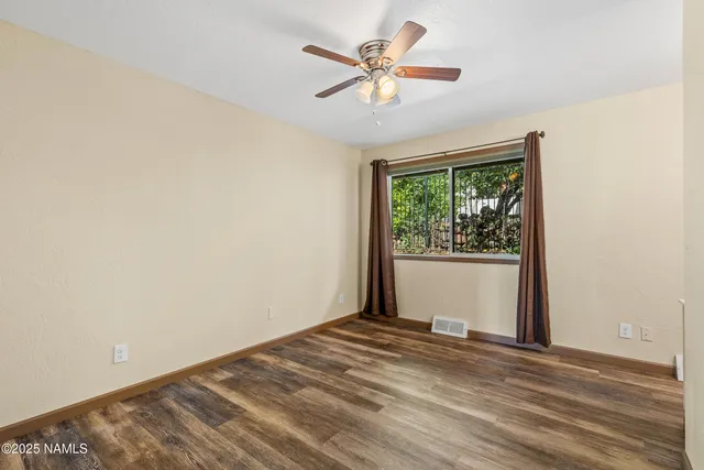 a view of a big room with wooden floor and a chandelier fan