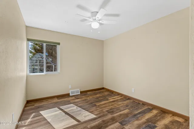 an empty room with a chandelier fan and windows