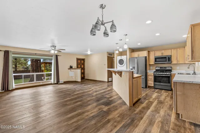 a kitchen with stainless steel appliances kitchen island wooden floors granite counter tops and a window