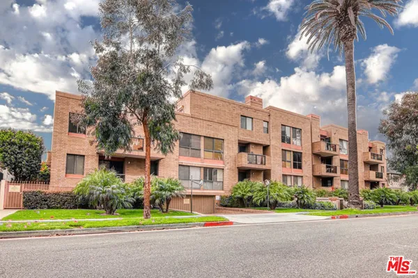 a front view of a multi story residential apartment building with yard and traffic signal