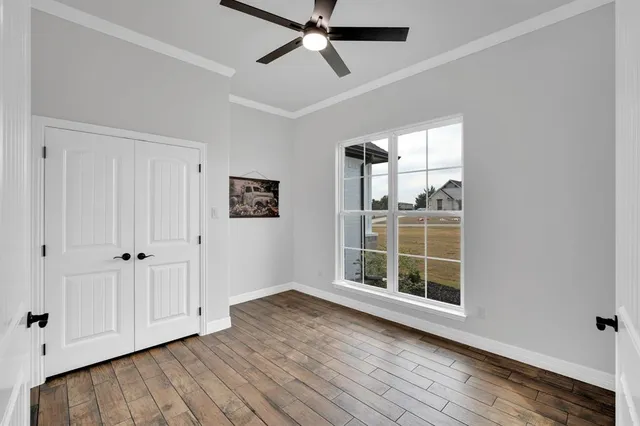 a view of empty room with wooden floor and fan