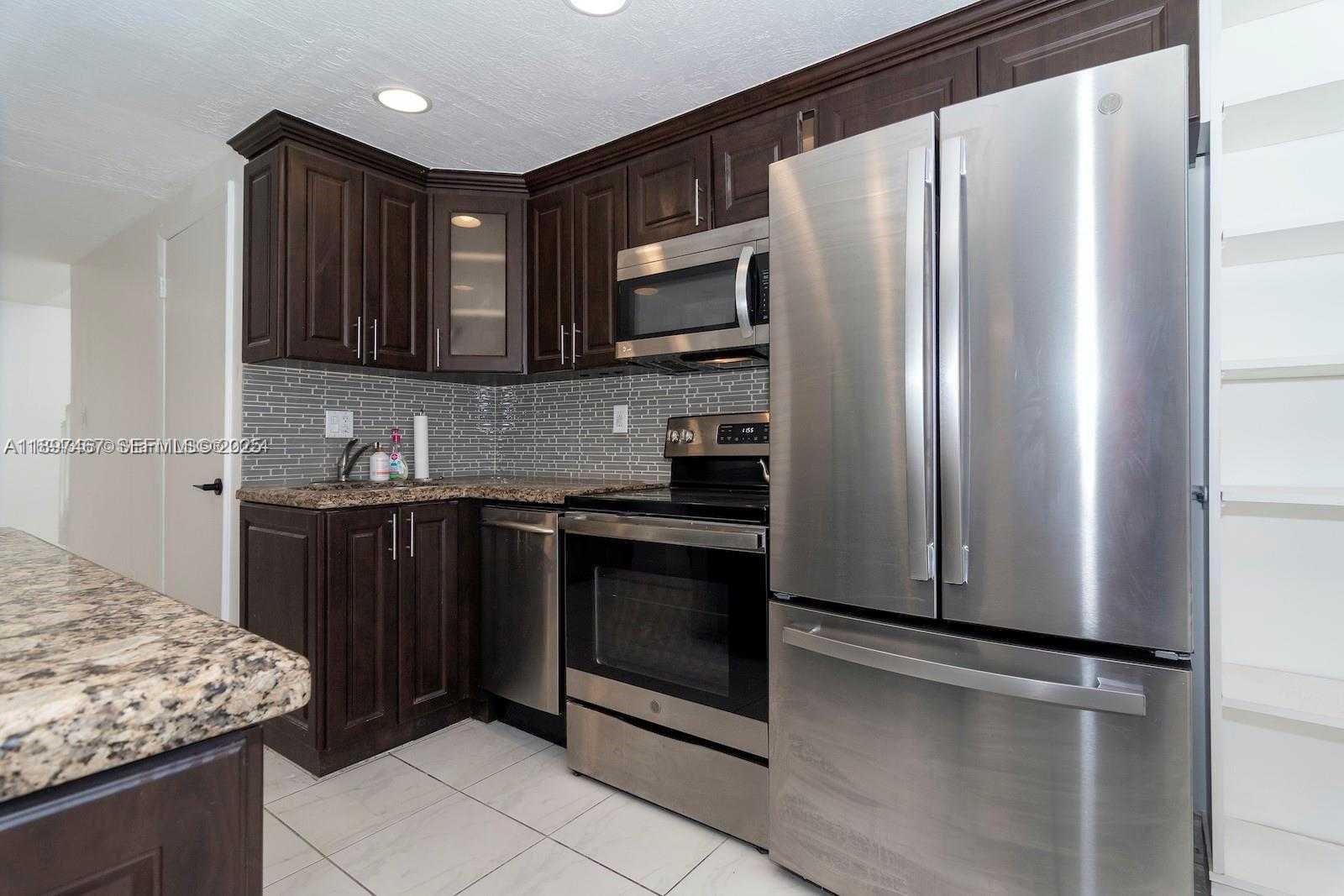 2729 Southwest 67th Avenue Miami, FL 33155 - Photo 17 of 39 a kitchen with stainless steel appliances granite countertop a refrigerator stove and microwave