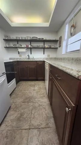 a kitchen with a sink a stove top oven and cabinetry