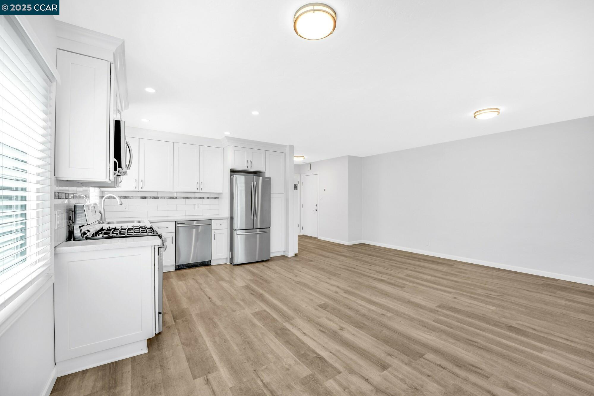1919 Curtis Street Berkeley, CA 94702 - Photo 24 of 54 a kitchen with granite countertop a refrigerator a stove a sink and white cabinets with wooden floor