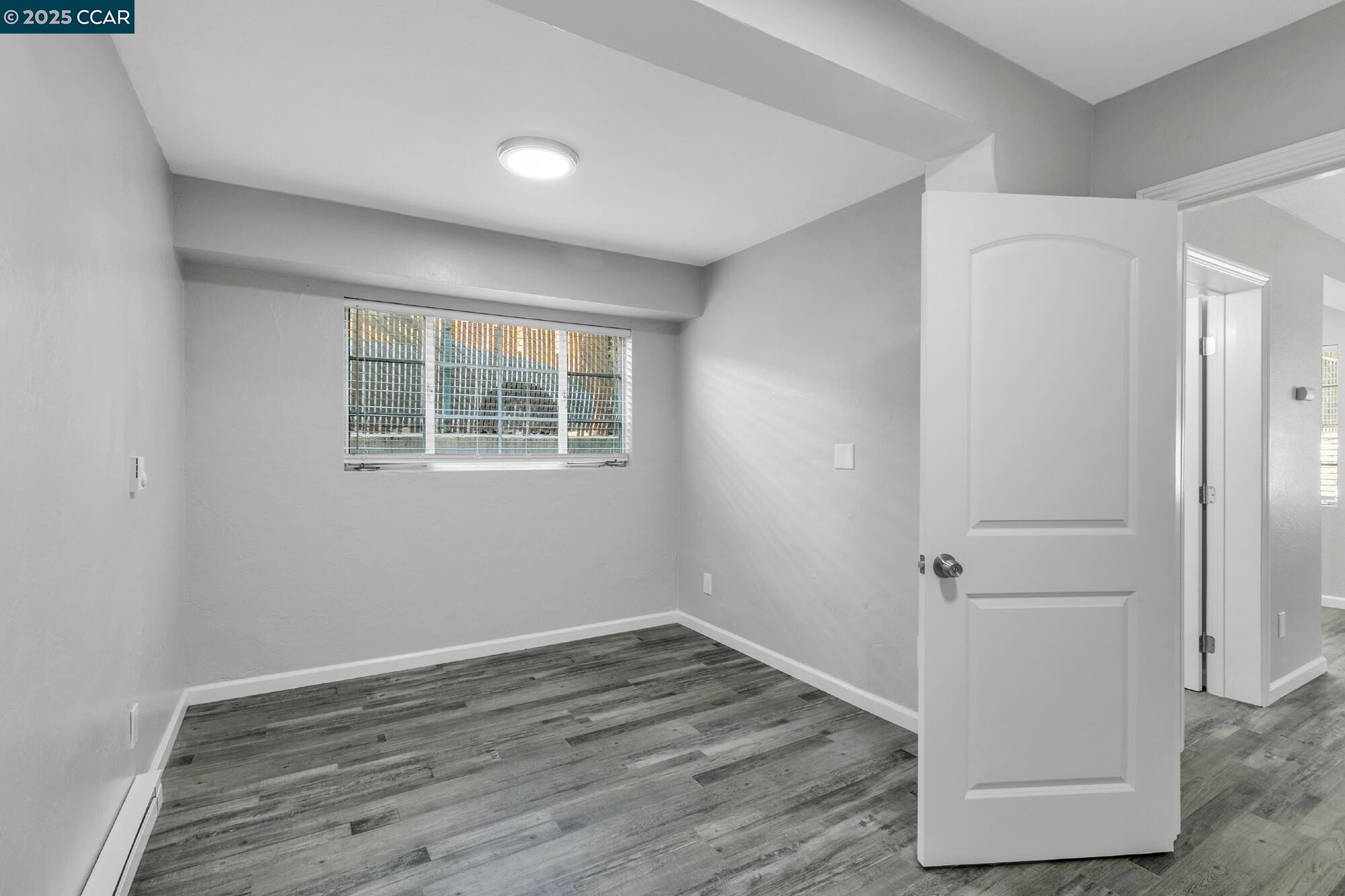 1919 Curtis Street Berkeley, CA 94702 - Photo 38 of 54 an empty room with wooden floor and windows