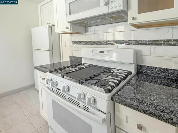 a kitchen with granite countertop a stove and a microwave