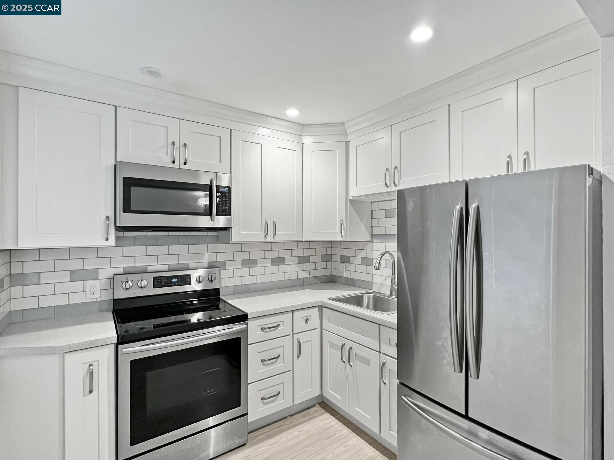 1919 Curtis Street Berkeley, CA 94702 - Photo 42 of 54 a kitchen with white cabinets and stainless steel appliances