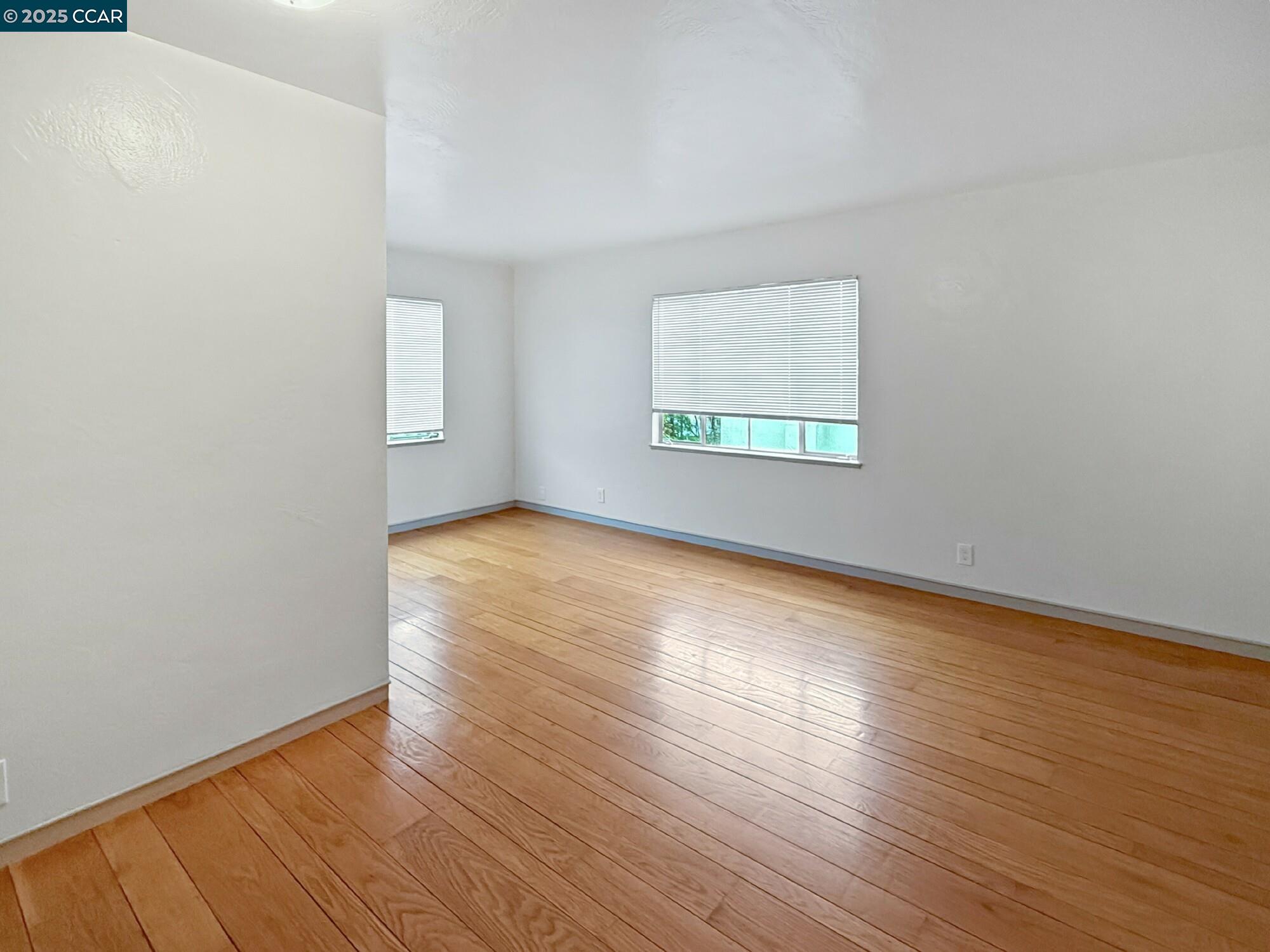 1919 Curtis Street Berkeley, CA 94702 - Photo 10 of 54 an empty room with wooden floor and windows