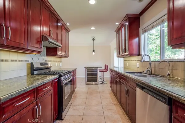 a kitchen with kitchen island granite countertop a sink stove and cabinets