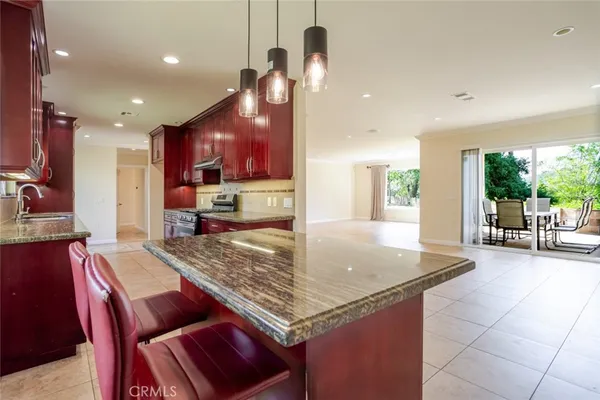 a kitchen with granite countertop kitchen island stainless steel appliances a table chairs sink and wooden floor